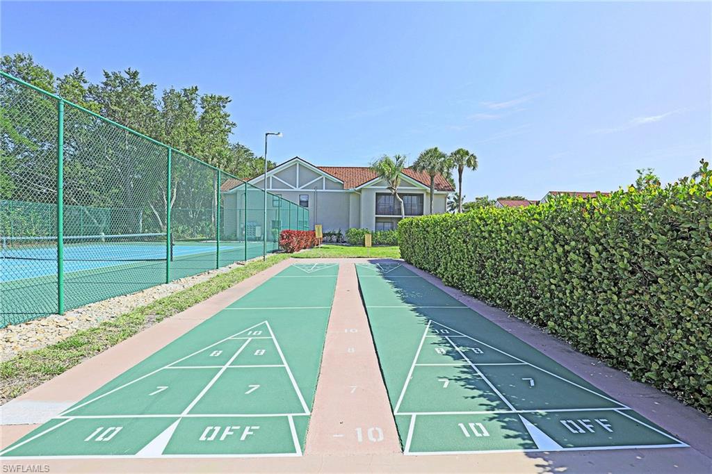 Dual shuffleboard courts, adjacent tennis court, perimeter fencing, and established privacy hedges