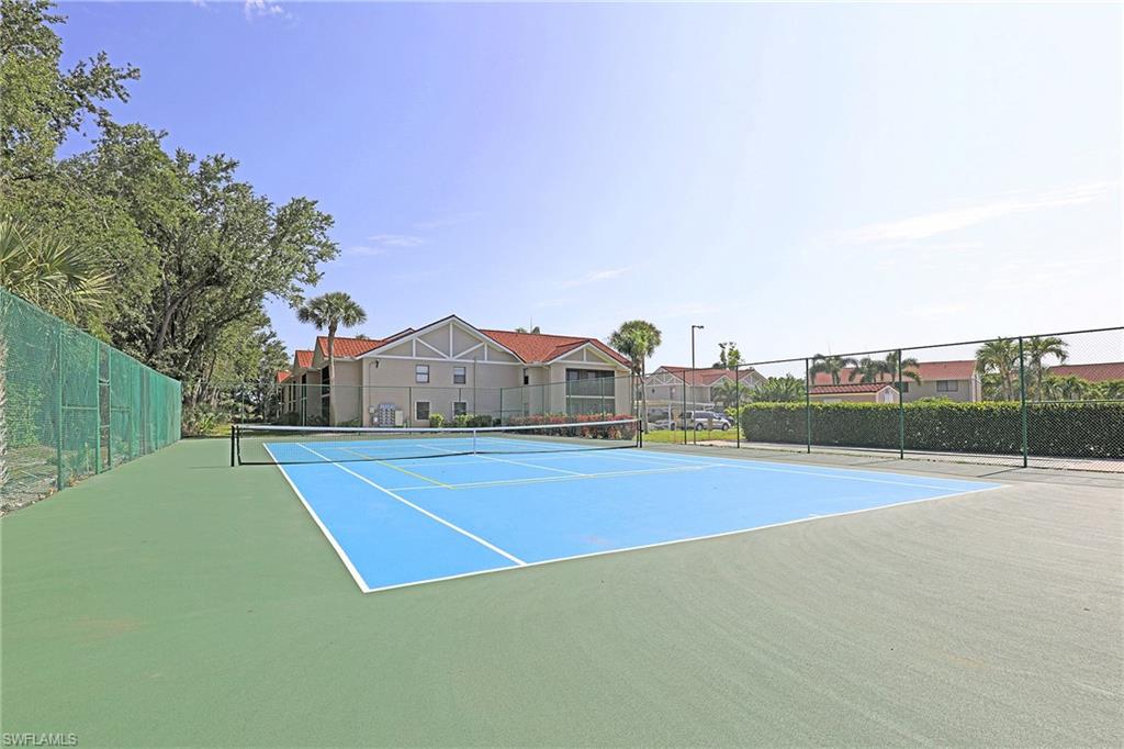 Tennis court with a blue playing surface, green surrounding court, and perimeter fencing