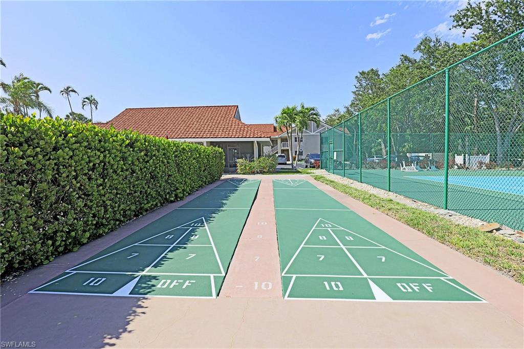 Dual shuffleboard courts, tennis court, and lush perimeter landscaping