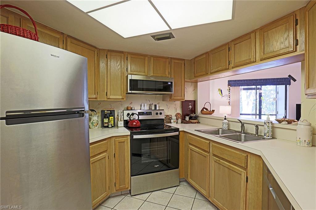 Kitchen featuring wood-finish cabinetry, stainless steel appliances, a dual basin sink, and a pass-through window