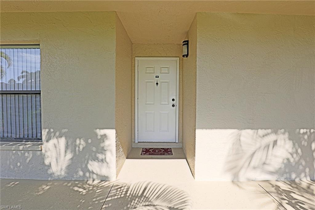 Entryway featuring a white paneled door, exterior wall sconce, and textured stucco walls