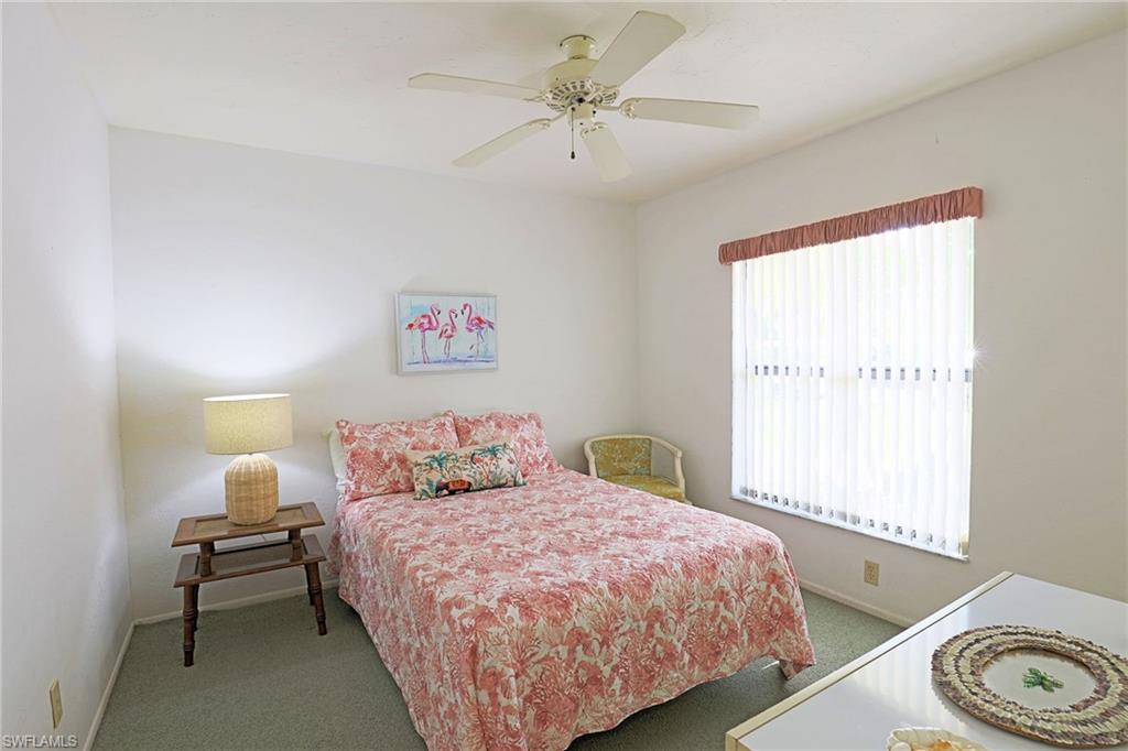 Recessed window with vertical blinds, ceiling fan, and light green carpet flooring