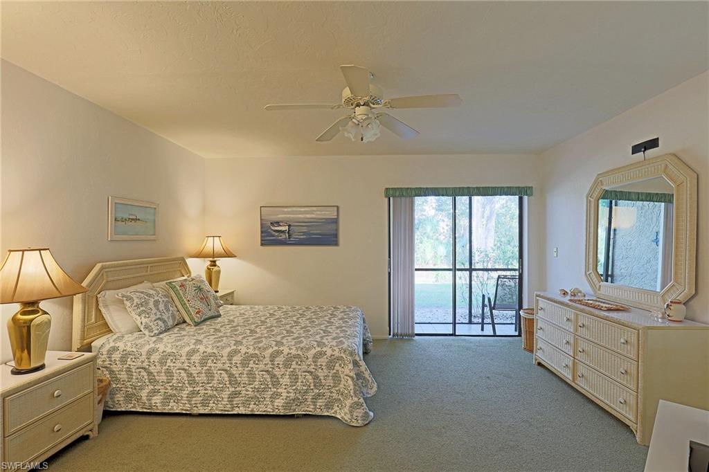 Sliding glass door to an outdoor area, ceiling fan with light fixture, light-colored walls, and carpeted flooring