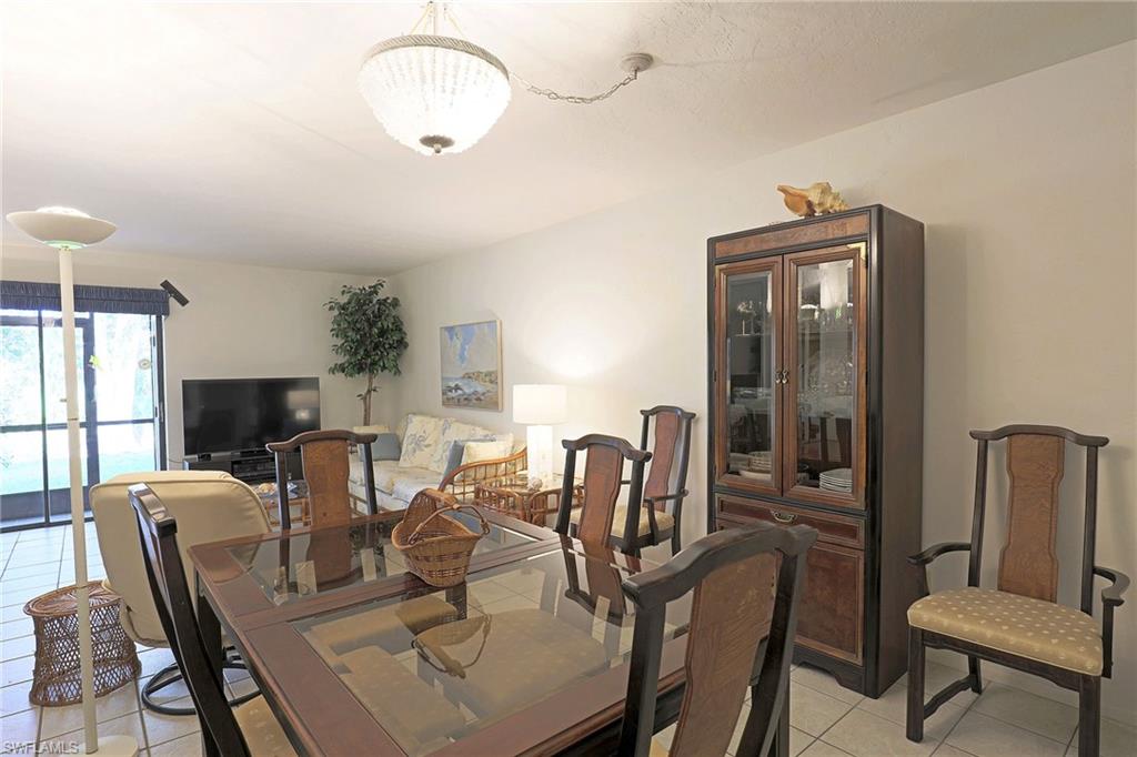 Dining area with a glass-top table, tile flooring, and a built-in display cabinet