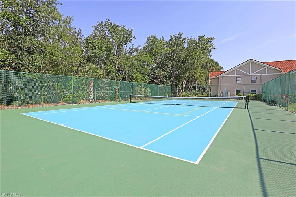 Tennis court featuring a synthetic playing surface, net, and green chain-link perimeter fencing