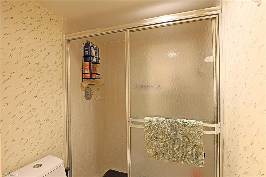 Shower enclosure with sliding frosted glass doors, a single-handle chrome shower faucet, and white tiled walls