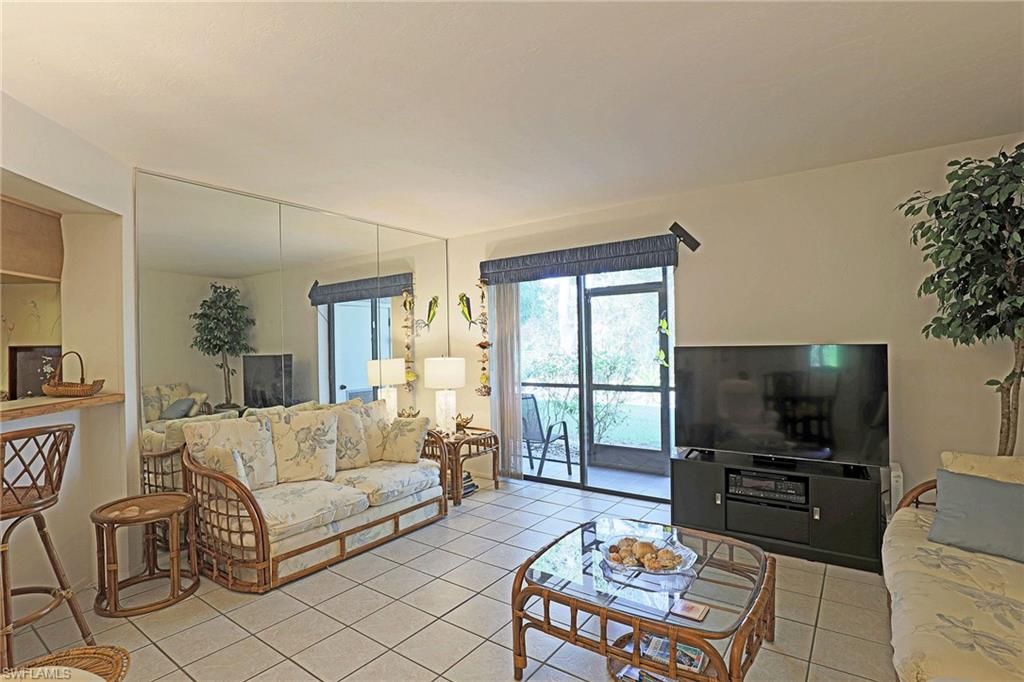 Tile flooring, full-wall mirrored accent, sliding glass doors, screened patio, and a breakfast bar