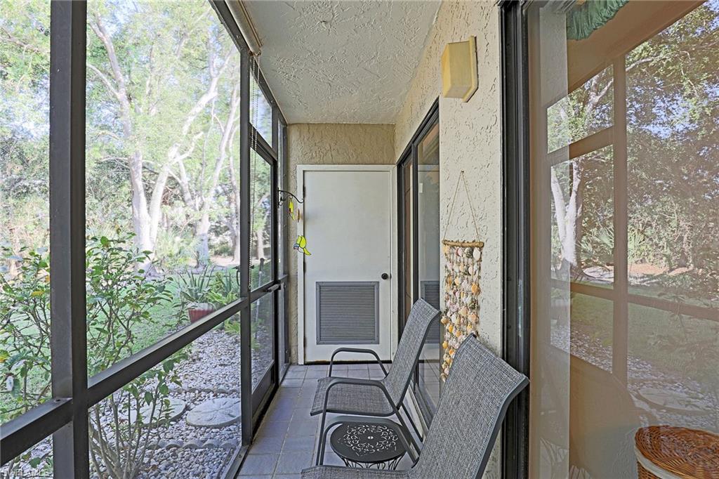 Enclosed screened patio featuring tile flooring, stucco exterior, and a permanent wall-mounted light fixture