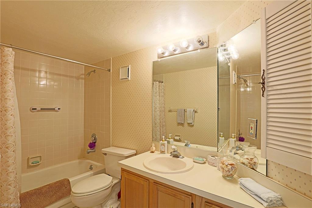 Built-in vanity with a single basin sink, large wall-mounted mirror, and overhead strip lighting