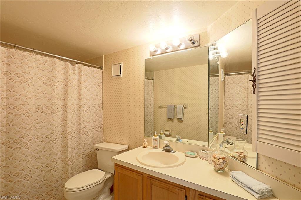Bathroom featuring a built-in vanity with a countertop sink, wood-finish cabinetry, and an overhead lighting fixture