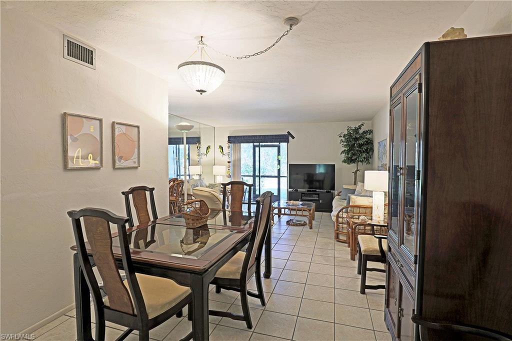 Tiled flooring, built-in display cabinet with glass doors, recessed lighting, and a chandelier-style ceiling fixture