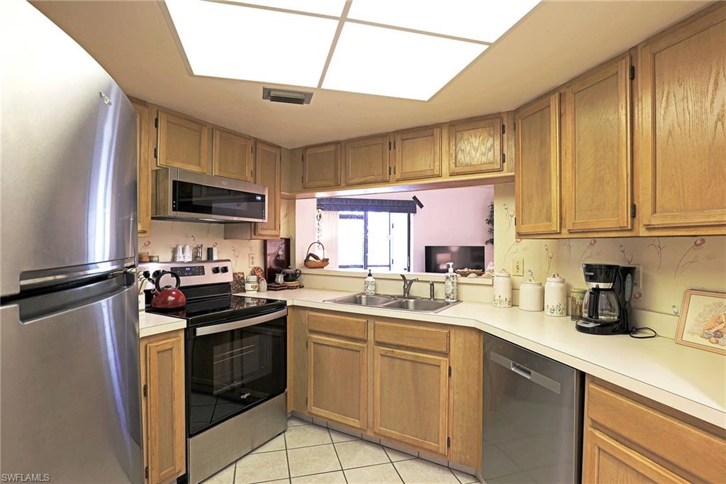 Kitchen with wood-finish cabinetry, stainless steel appliances, white countertops, and a double basin sink