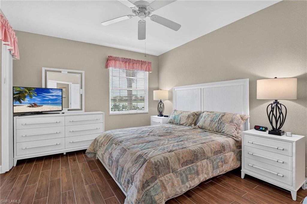 Primary bedroom with Wood-finish flooring, ceiling fan, window with blinds, and neutral wall tones