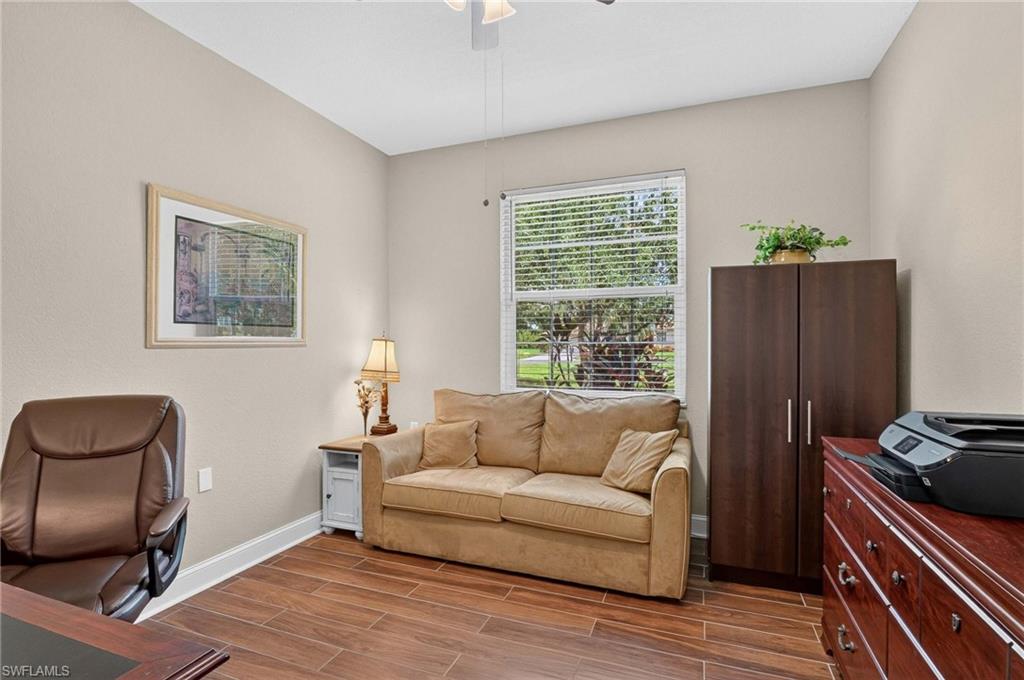 Den with Wood-finish flooring, neutral wall paint, and a window with blinds providing natural light. Sofa is a sleeper for additional guests.