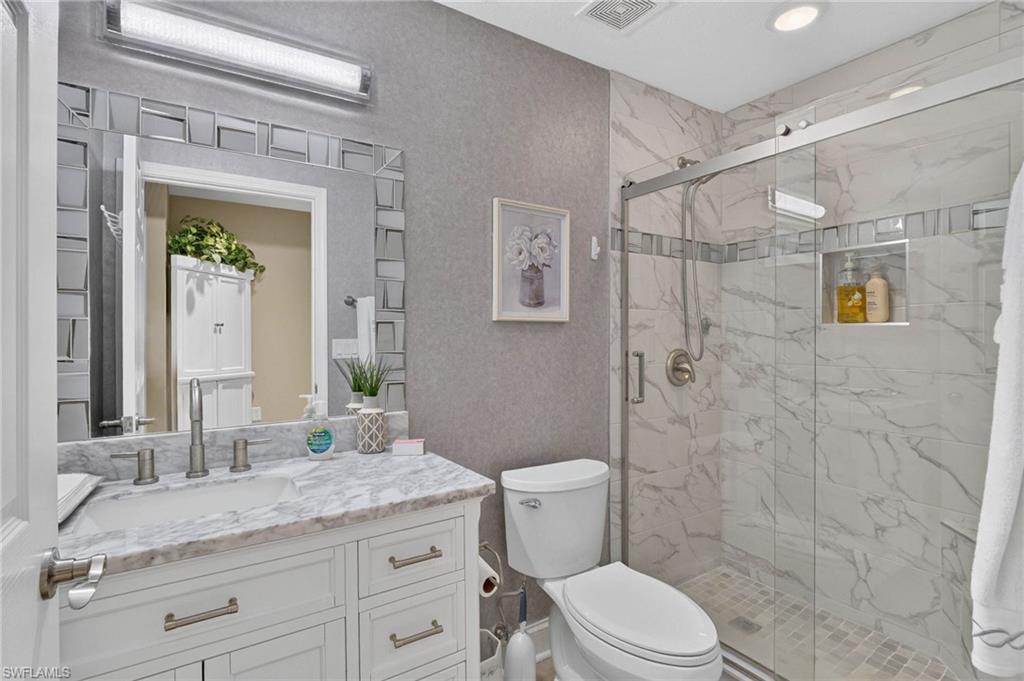 Guest bathroom with White vanity with a marble-finish countertop, undermount sink, and brushed nickel fixtures