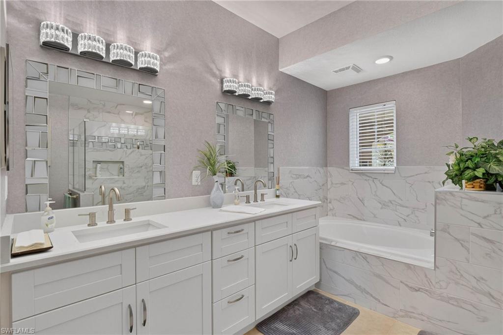 Primary bath Dual vanity with white shaker-style cabinetry and brushed nickel hardware