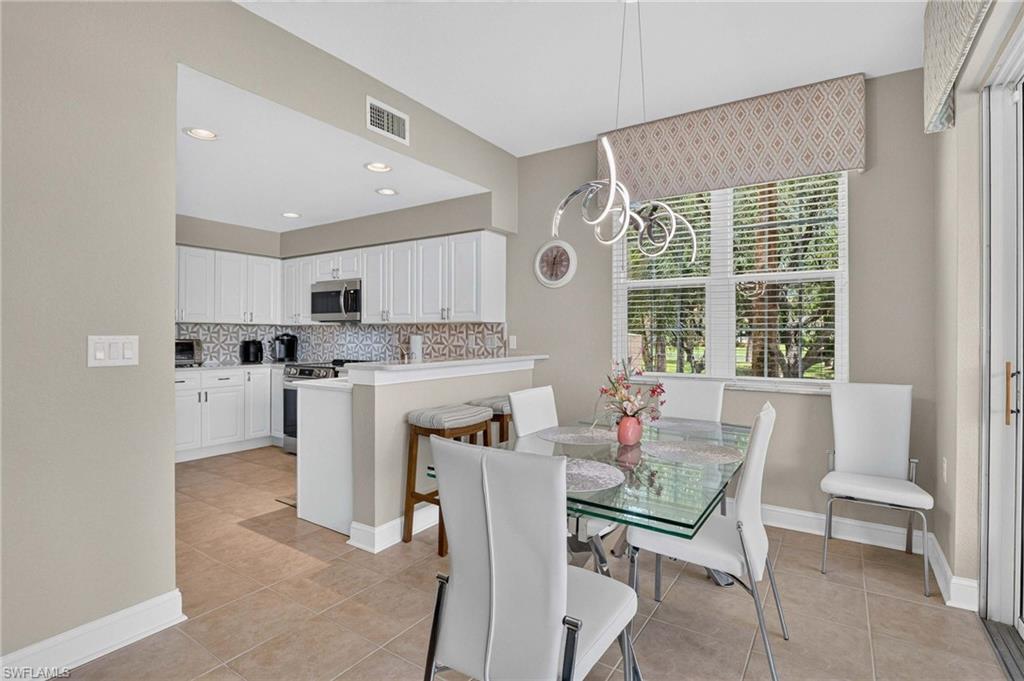 Recessed lighting, tile flooring, white shaker-style cabinetry, and stainless steel appliances