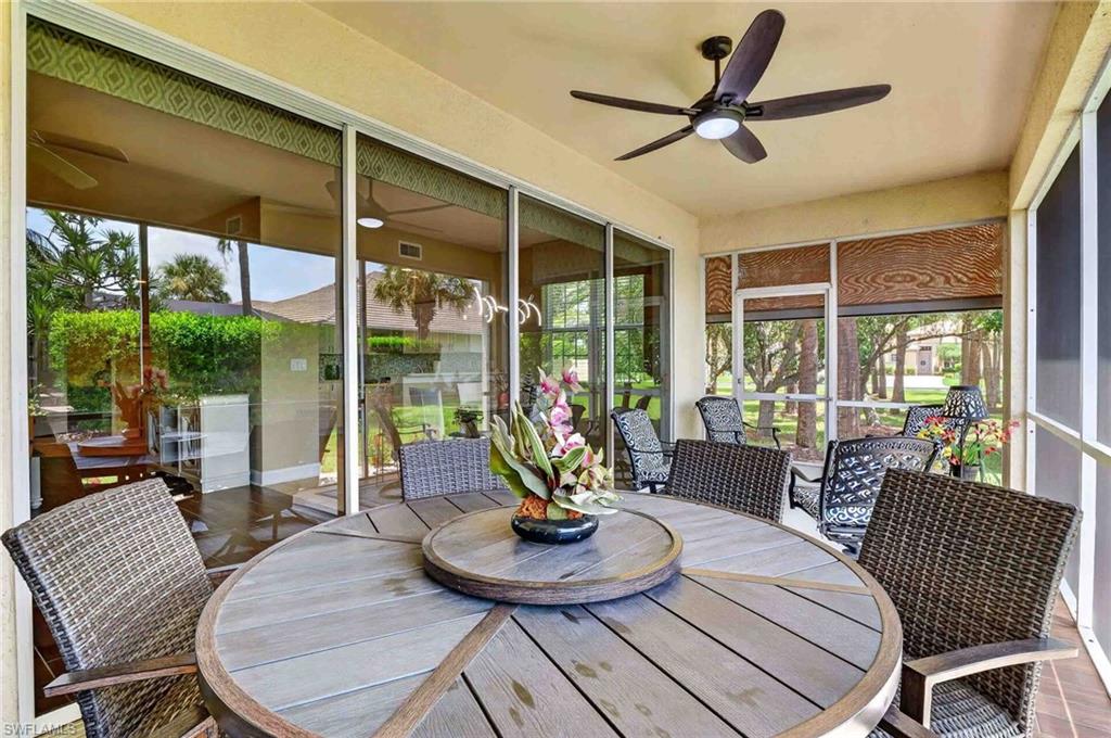 Screened lanai with a ceiling fan, sliding glass doors, and a wood-look composite round table