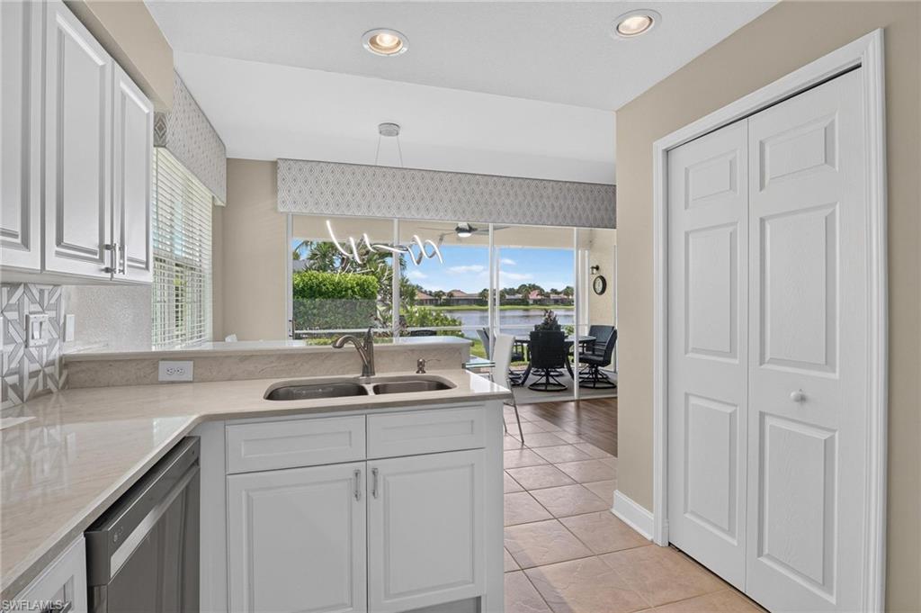 Kitchen featuring white cabinetry, light-toned countertops, a mosaic tile backsplash, and a double basin sink