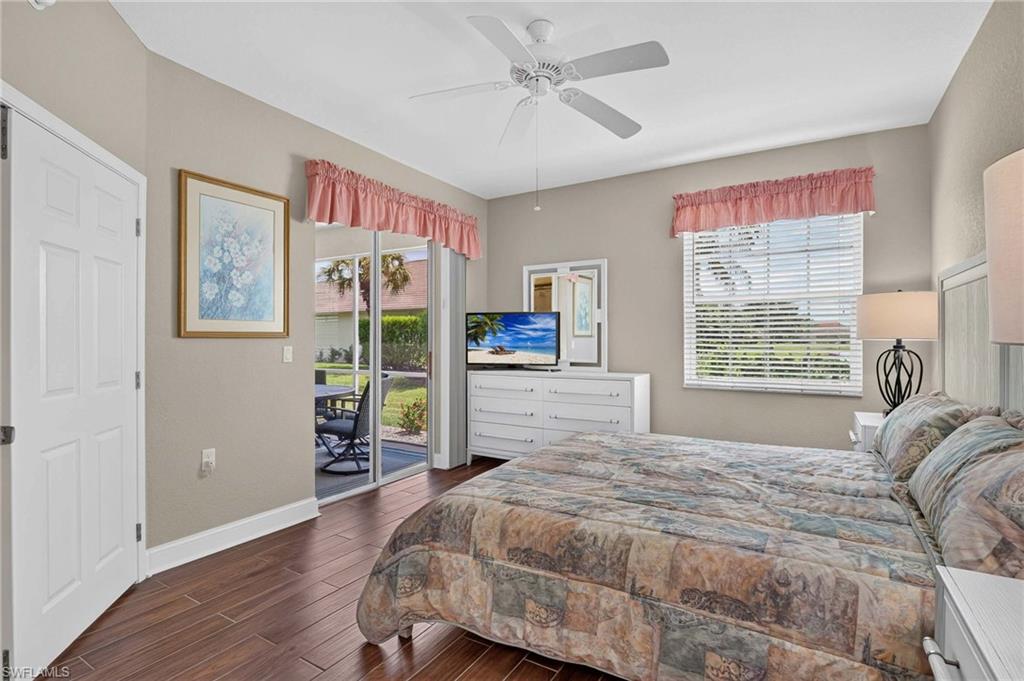 Wood-finish flooring, ceiling fan, white paneled door, sliding glass door with screened lanai, and a window with blinds