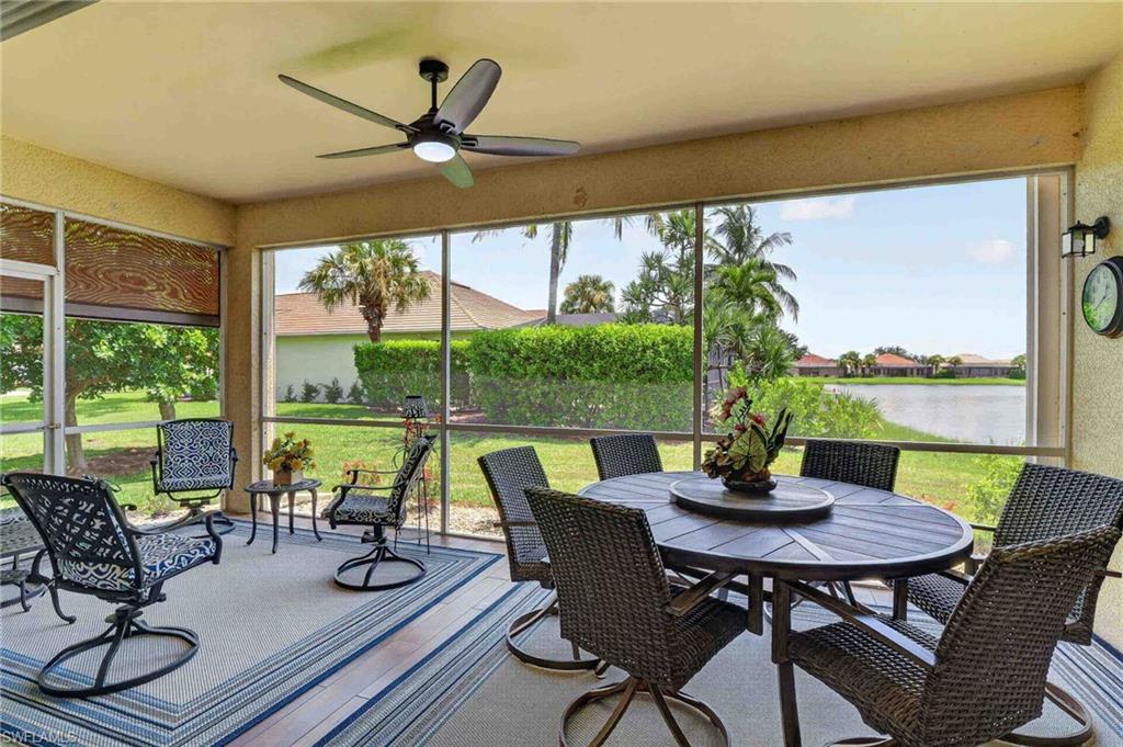 Screened outdoor living area featuring a ceiling fan with integrated lighting, a tranquil water feature, and a well-maintained lawn