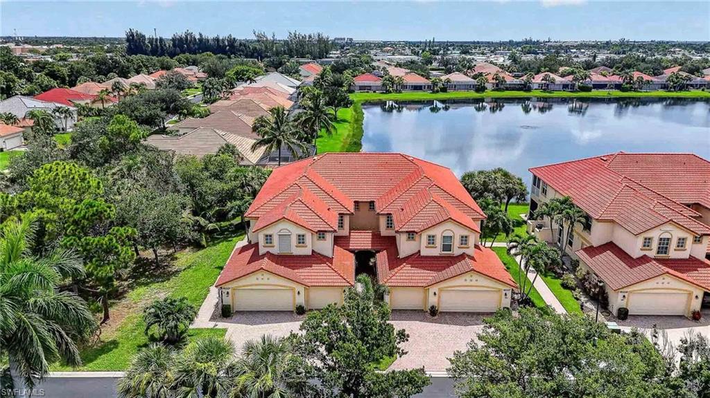 Two-story duplex with tile roof, paver driveway, attached two-car garages, and mature landscaping