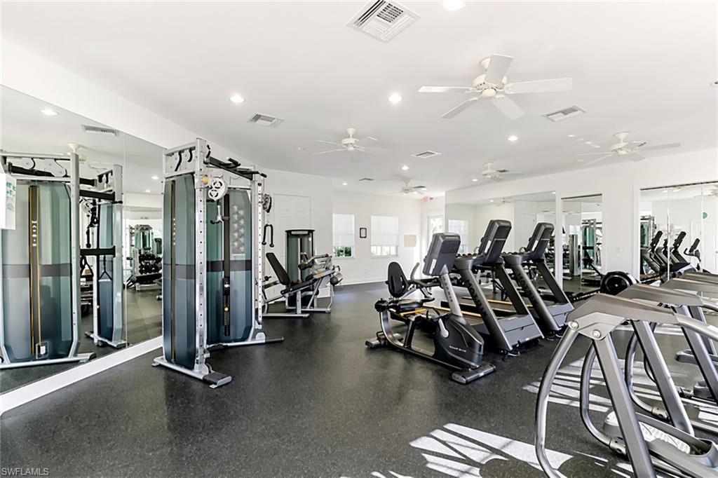 Fitness room with rubber flooring, extensive mirrored walls, recessed lighting, multiple ceiling fans, and various exercise machines