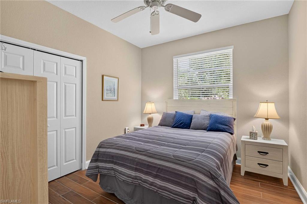 Bright secondary bedroom featuring wood-finish flooring, soft neutral wall tones, and ample natural light from a large double-hung window.