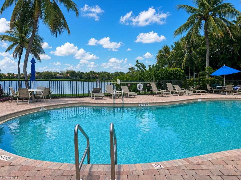 Swimming pool with a brick paver deck, stainless steel pool rails, and surrounding tropical foliage