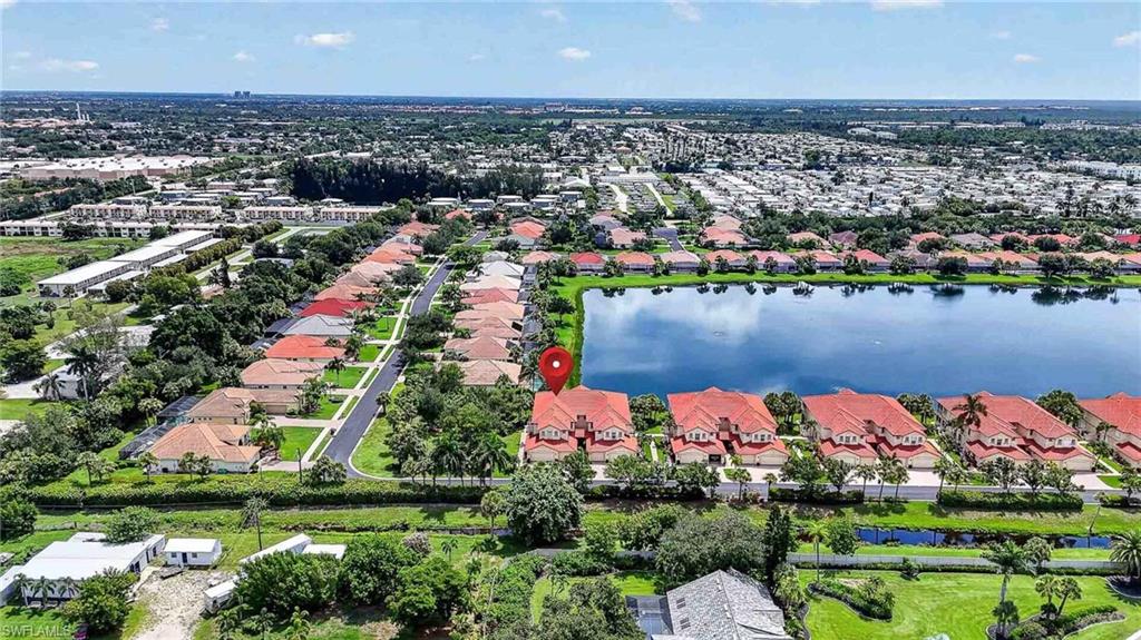 Expansive neighborhood featuring a large lake, mature landscaping, and residential properties with tiled roofs