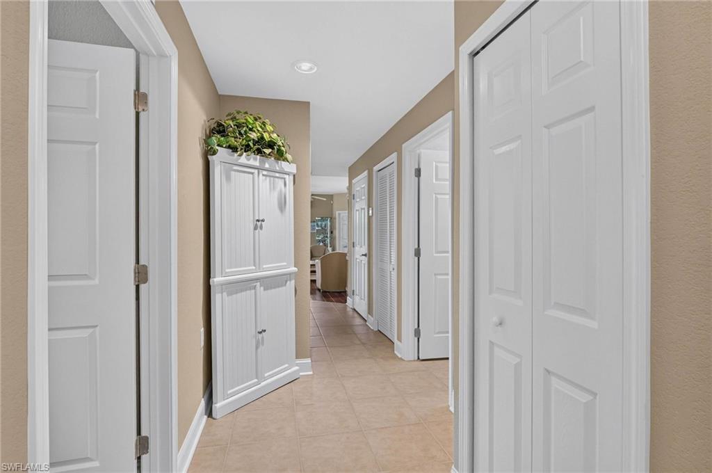 View of entry from 2 car garage. Tiled flooring extending through a hallway with multiple paneled doors and recessed lighting