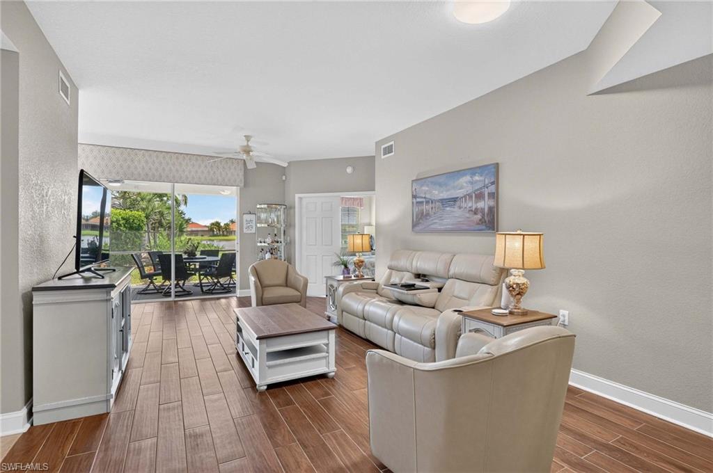 Wood-finish flooring throughout, sliding glass door with outdoor screened lanai, a ceiling fan, recessed lighting, and neutral wall tones