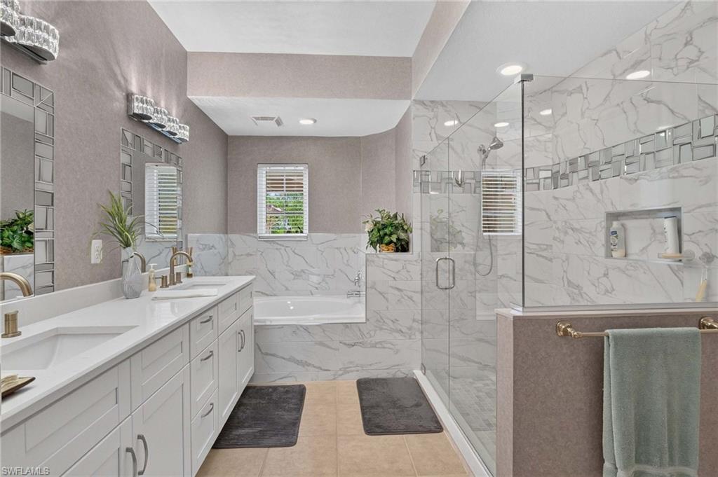 Primary bath with Dual vanity with white shaker-style cabinetry and a light-colored countertop
