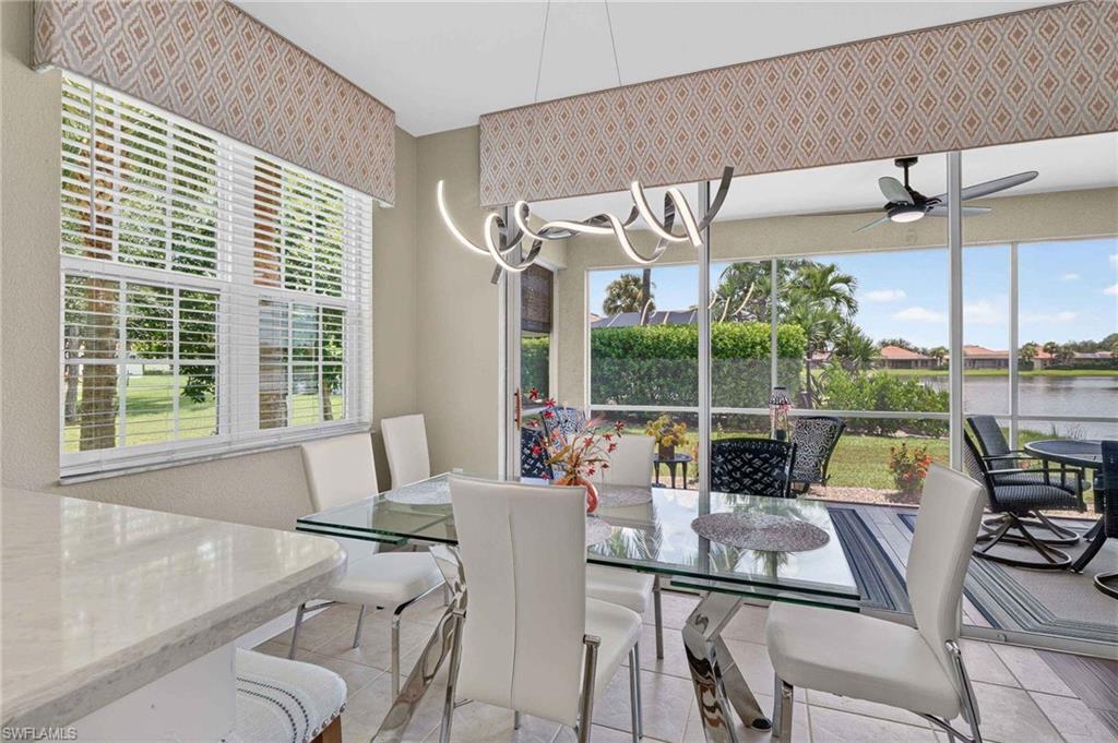 Dining area with tile flooring, a modern chandelier, and access to a screened lanai featuring a ceiling fan and water views