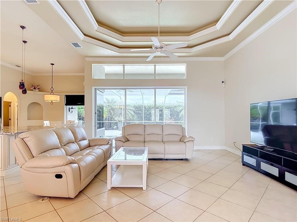 Tray ceiling with crown molding, tile flooring, sliding glass doors, transom windows, and built-in arch details
