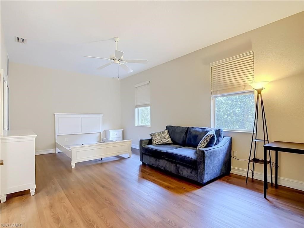 Wood-finish flooring, high vaulted ceilings, ceiling fan, and multiple windows with blinds
