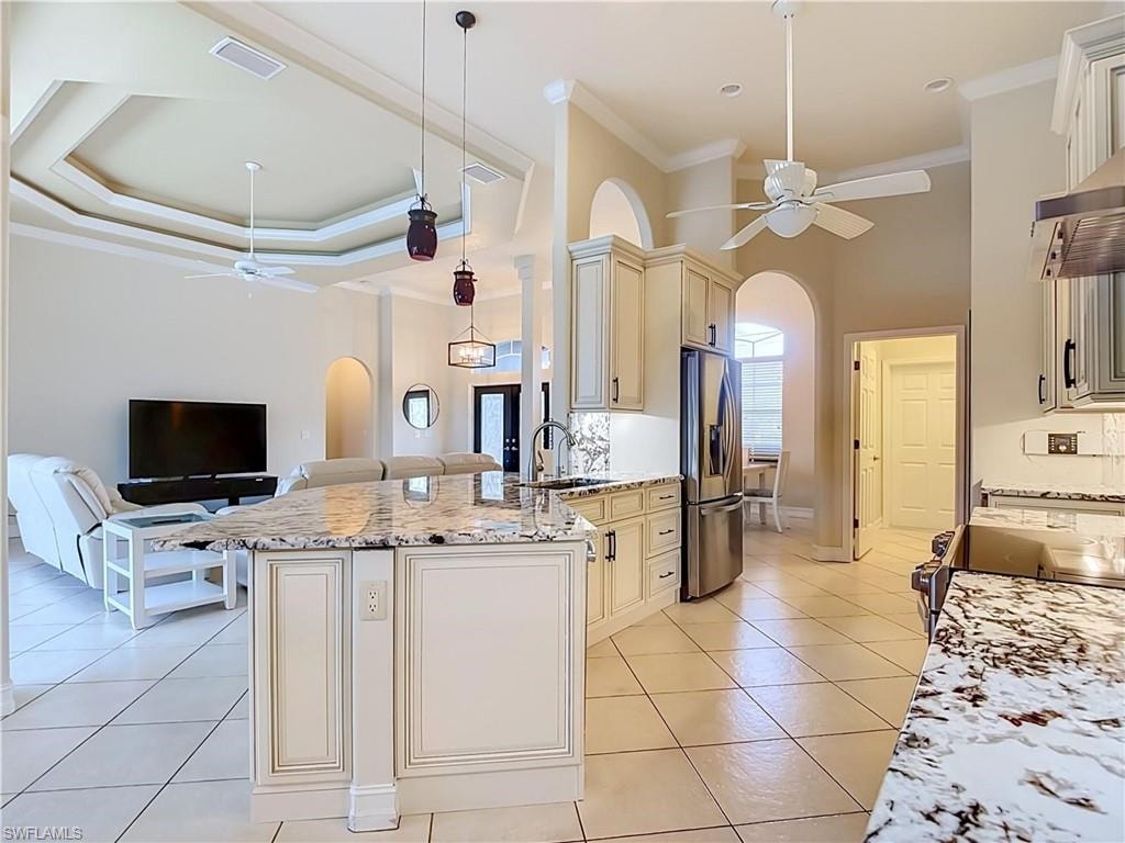 Kitchen featuring granite countertops, stainless steel appliances, tile flooring, and custom cabinetry with an integrated breakfast bar