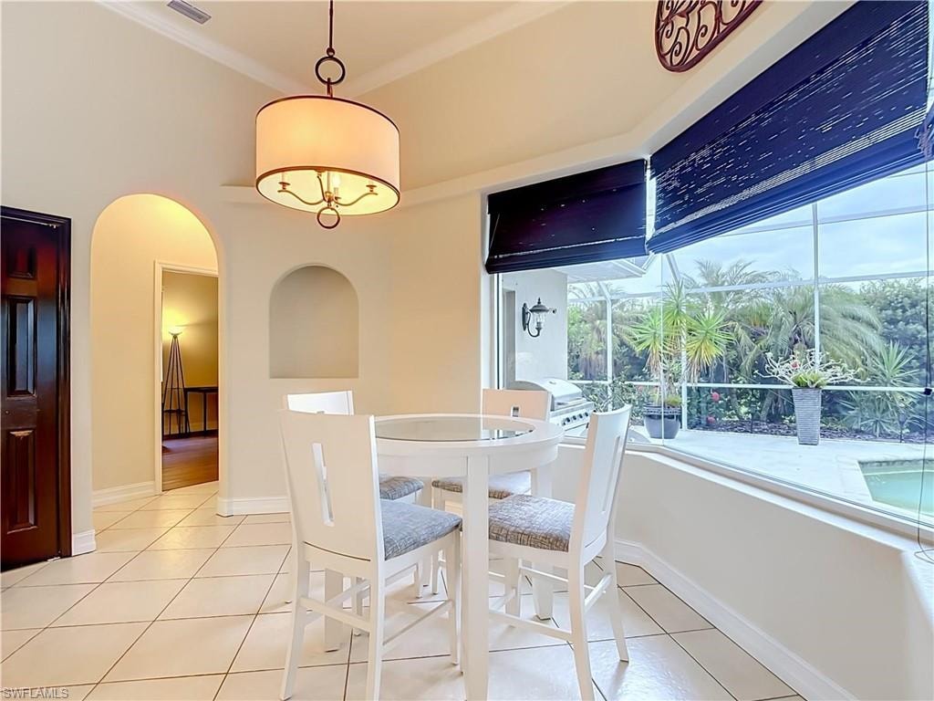Tiled flooring, vaulted ceiling, arched doorway, recessed wall niche, and an expansive window with outdoor views