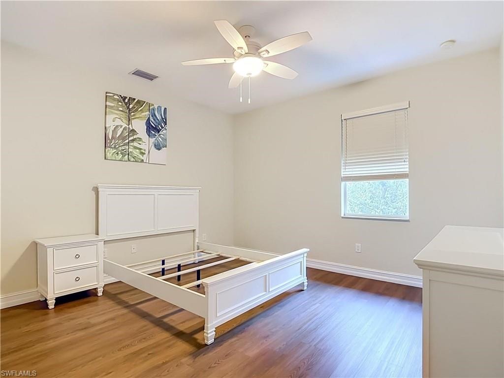 Wood-finish flooring, ceiling fan with integrated lighting, window with blinds, and light-toned wall finishes