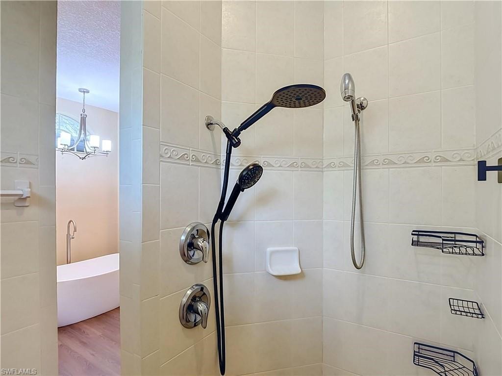 Tiled shower enclosure featuring dual shower heads with chrome and matte black finishes, integrated shower caddies, and decorative trim
