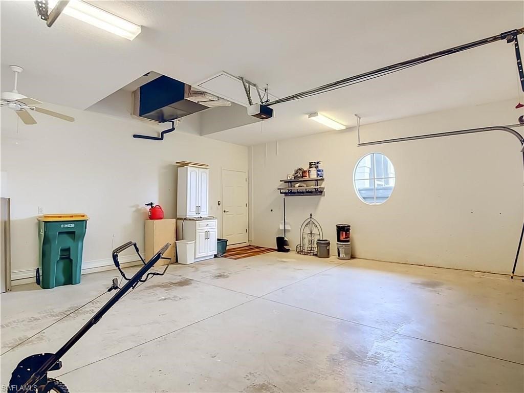 Concrete flooring, white cabinetry, oval window, overhead lighting, ceiling fan