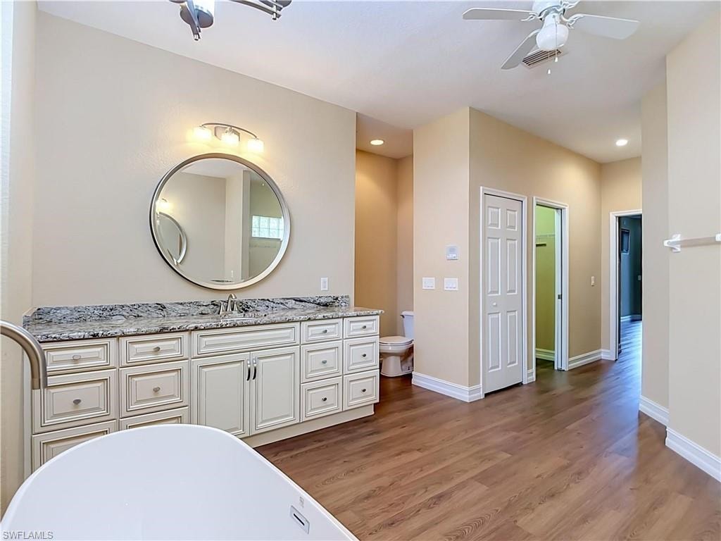 Spacious vanity with a stone countertop, dual sinks, and extensive cabinetry