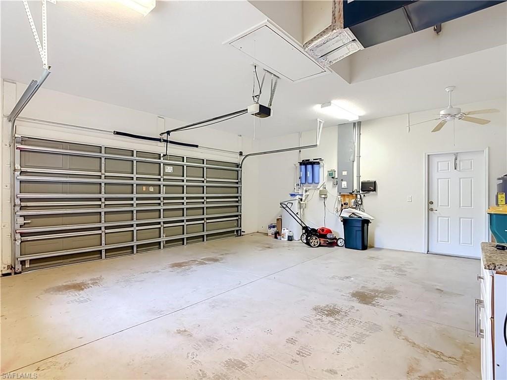 Two-car garage with a paneled overhead door, concrete flooring, overhead lighting, and a ceiling fan