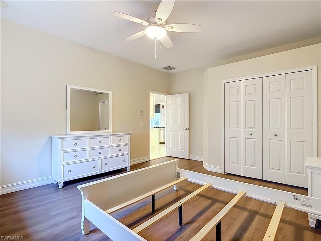 Wood-finish flooring, ceiling fan with integrated lighting, and a bi-fold closet with panel doors