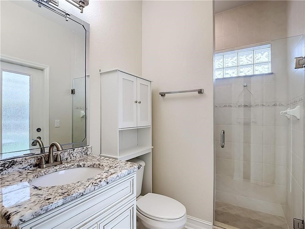 Vanity with a stone countertop, an undermount sink, and a brushed nickel faucet