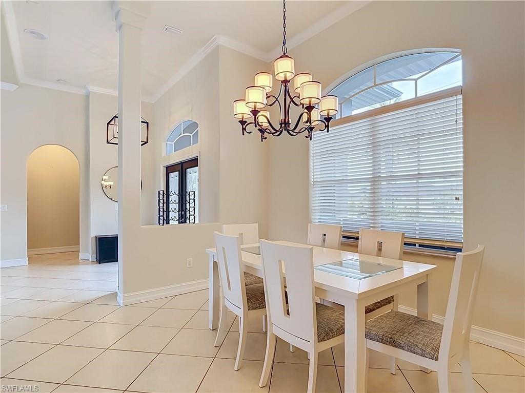 Dining area featuring a multi-light chandelier, arched window with horizontal blinds, and tiled flooring