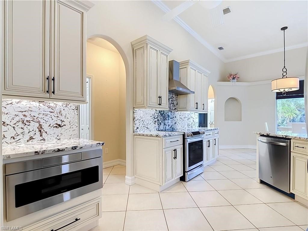 Kitchen featuring white cabinetry, light-toned tile flooring, stainless steel appliances, and a vaulted ceiling