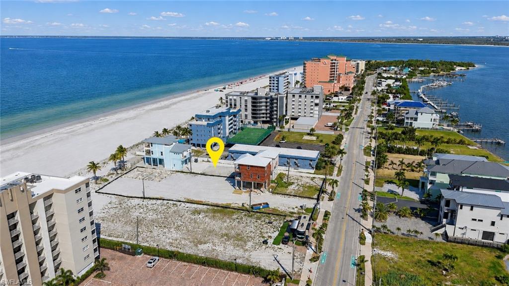 Expansive land parcel with direct access to a paved road, positioned across from a sandy beach and deep blue water - Virtually Edited Image