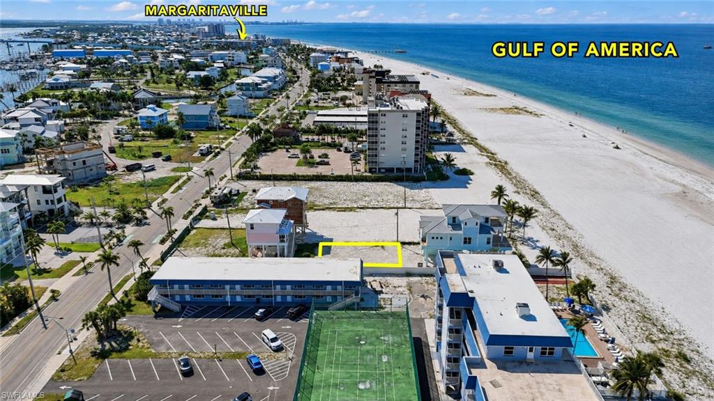 Gulf-front lot with direct beach access, situated across from a street with established properties and a marina - Virtually Edited Image
