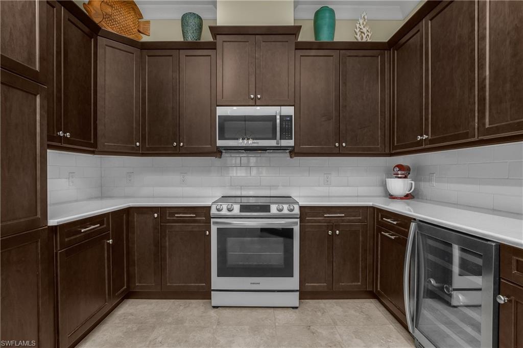 U-shaped kitchen with dark wood cabinetry, white countertops, white subway tile backsplash, and stainless steel appliances